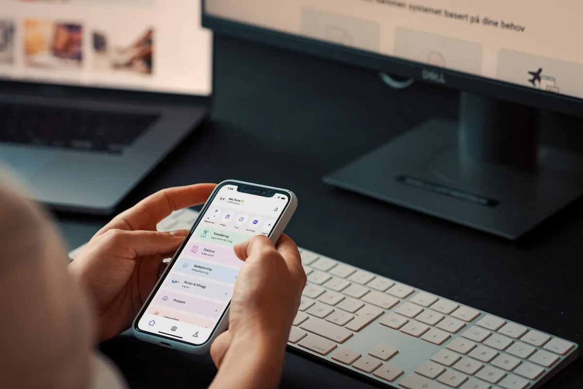 To hender som holder en mobiltelefon med Tripletex-appen åpen