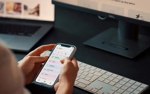 To hender som holder en mobiltelefon med Tripletex-appen åpen